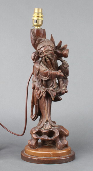 A Chinese carved root wood table lamp figure of a standing gentleman with ivory teeth, raised on an oval base 39cm h x 16cm w x 12cm d