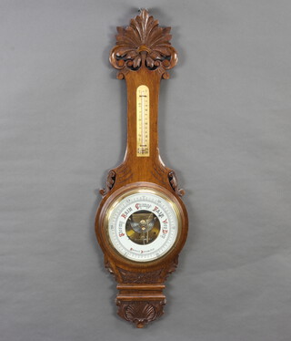 An aneroid barometer and thermometer contained in a carved oak wheel case with porcelain dial 90cm h x 26cm 