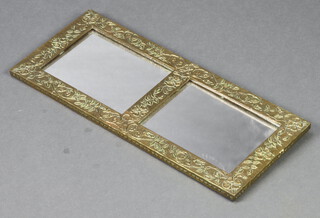 A rectangular plate wall mirror contained in an embossed brass frame 23cm x 55cm 