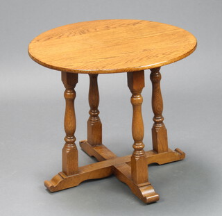 A circular oak occasional table raised on turned supports with X framed stretcher 46cm x 53cm diam. 