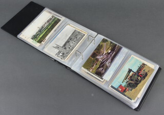 A collection of coloured and black and white postcards contained in a green album 