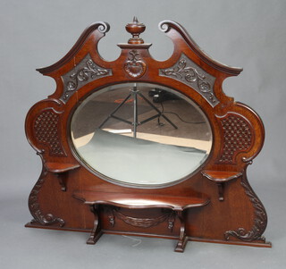 An oval plate over mantel mirror contained in a shaped mahogany frame with broken pediment and shelves 101cm x 120cm 