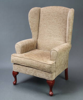 A winged armchair upholstered in light brown material, raised on cabriole supports 106cm h x 70cm x 57cm (seat 38cm x 36cm) 