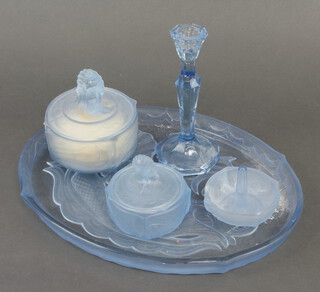 An Art Deco blue moulded glass dressing table set decorated with a mermaid and fish comprising a tray, jar and cover, ringstand, smaller jar and cover and a candlestick
