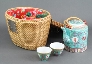 A modern famille rose teapot and 2 bowls contained in a wicker basket 