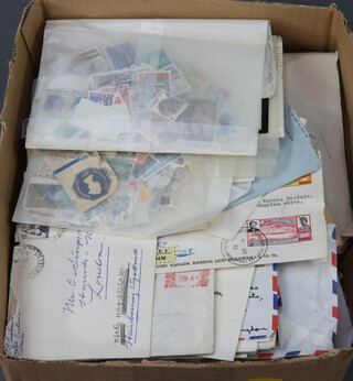 A collection of stamped envelopes, loose stamps etc contained in a shallow box 

