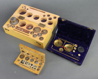A gilt metal balance contained in a plush case, 2 sets of weights contained in beech cases (2 weights missing
