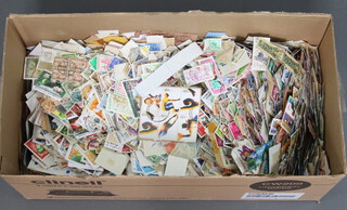 A collection of loose world stamps in a shallow box
