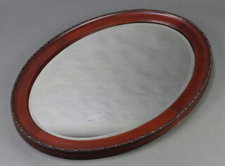 An oval bevelled plate wall mirror contained in a mahogany frame 71cm h x 96cm w 