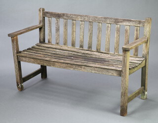 A well weathered wooden slatted garden bench 67cm h x 124cm w x 51cm d (seat 107cm x 39cm, split to 1 side) 