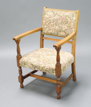 A 1930's oak open arm chair upholstered in tapestry material, raised on turned supports 78cm h x 51cm w x 47cm d (seat 28cm x 30cm) 