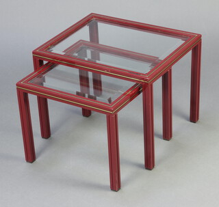 Pierre Vandel, a mid-Century nest of 2 red and gilt metal interfitting coffee tables with bevelled plate glass tops 38cm h x 49.5cm w x 40cm d (slight scratch to the glass, contact marks to the edge) and 34cm h x 40.5cm w x 40cm d 