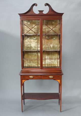 An Edwardian inlaid mahogany display cabinet on stand with broken pediment, fitted adjustable shelves enclosed by astragal glazed panelled doors, the base fitted 2 drawers above a shaped undertier, raised on square tapered supports 221cm h x 99cm w x 42cm d 