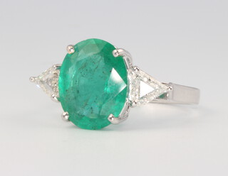 An 18ct white gold oval emerald and diamond ring, the centre cut stone approx 3.89ct, the triangular cut diamonds 0.61ct, size M 1/2, 4.2 grams 