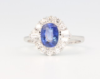 An 18ct white gold oval sapphire and diamond cluster ring, the oval cut stone approx. 1.74ct flanked with brilliant and tapered baguette diamonds 0.5ct, size M 1/2, 3.5 grams