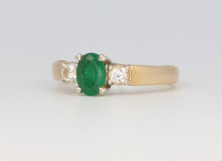 A 14ct yellow gold oval emerald and diamond ring, the centre emerald approx. 0.75ct (rubbed) the 2 brilliant cut diamonds 0.3ct, size M 1/2, 4.8 grams