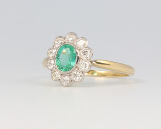 An 18ct yellow gold oval emerald and diamond cluster ring, the centre stone 0.4ct, the brilliant cut diamonds 0.6ct, size N, 2.8 grams