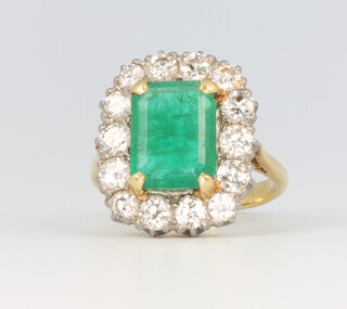 A yellow metal stamped 18ct rectangular emerald and diamond cluster ring, the centre stone approx. 11mm x 8mm, the 14 brilliant cut diamonds each 0.10ct, size N 1/2, 7.7 grams 