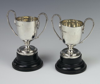 A pair of Edwardian silver 2 handled trophy cups on wooden socles 9cm, 176 grams, Chester 1910 