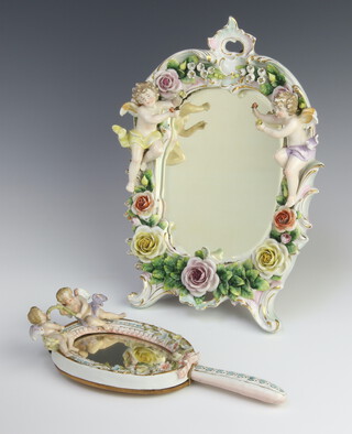 A 20th Century German porcelain easel mirror decorated with cherubs and encrusted flowers 31cm together with a ditto hand mirror 27cm 