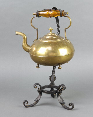 A circular brass tea kettle with amber glass handle, raised on an iron stand 28cm x 21cm x 20cm (burner missing) 