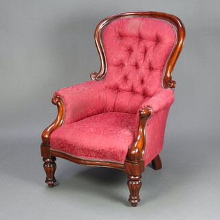 A Victorian carved mahogany show frame armchair upholstered in red buttoned material, raised on turned and reeded supports 104cm h x 74cm w x 66cm d (seat 36cm x 46cm) 
