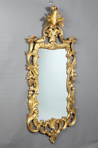 A 20th Century Rococo style plate mirror contained in a carved giltwood and pierced hardwood frame surmounted by a scroll 120cm h x 56cm w 