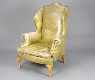 A Georgian style winged armchair upholstered in green leather, raised on cabriole supports 105cm h x 74cm w x 69cm d (seat 38cm x 41cm) 