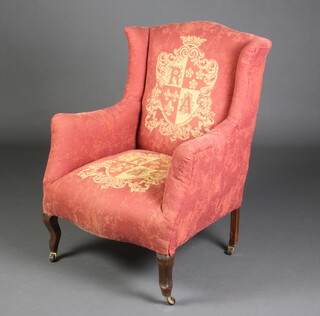 An Edwardian winged armchair upholstered in gold armorial material, raised on cabriole supports 94cm h x 70cm w x 60cm d (seat 32cm x 34cm) 