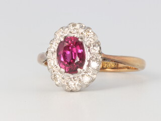 An 18ct oval ruby and diamond ring, the ruby approx. 0.5ct surrounded by brilliant cut diamonds 2.7 grams, size I 