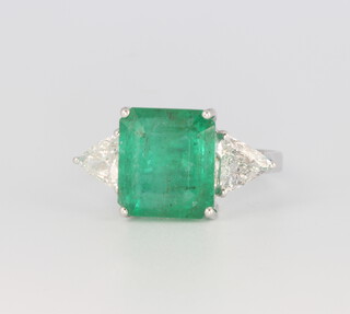 An 18ct white gold emerald cut emerald flanked by triangular cut diamonds, the centre stone 6.48ct, the diamonds 0.9ct, 4.9 grams, size N 