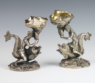 A pair of Victorian cast silver plated table salts, in the form of a sea god and goddess riding dolphins holding aloft gilt interior shell bowls, 16cm 