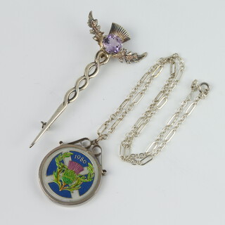 An enamelled 1986 two pound coin in a silver mount with chain together with a silver kilt pin with amethyst stone 