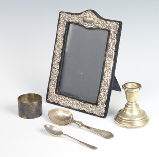 A silver napkin ring Sheffield 1952, 2 silver spoons 84 grams, a repousse silver photograph frame and a dwarf silver candlestick 