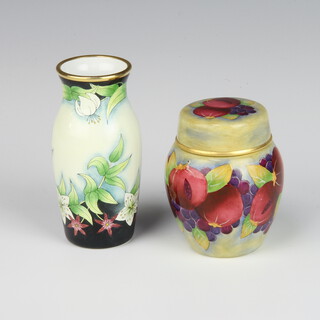A Moorcroft enamelled vase and cover decorated with fruit 7cm together with an oviform vase decorated with flowers 9cm 