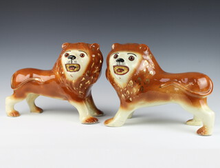 A pair of Victorian Staffordshire figures of standing lions with glass eyes and open mouths 26cm 