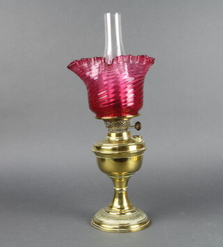 A Victorian brass oil lamp with clear glass chimney, shaped "cranberry" glass shade, the burner button marked English Duplex 49cm h x 16cm  