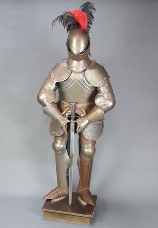 A 20th Century Maximillion style suit of armour complete with helmet and double bladed toledo sword, raised on a square base 166cm h x 70cm w x 38cm d 