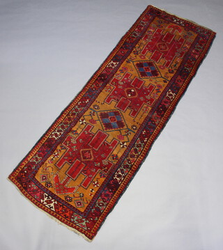 A red and tan ground Heriz runner with stylised medallions to the centre within a 3 row border 301cm x 108cm 