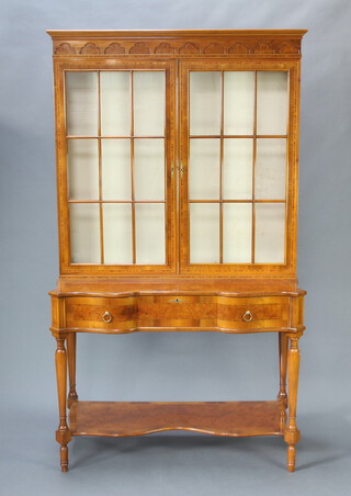 Signoretto, a Georgian style inlaid satinwood display cabinet, the raised back with moulded cornice, fitted adjustable shelves above 1 drawer, raised on turned supports with undertier 210cm h x 121cm w x 151cm d  