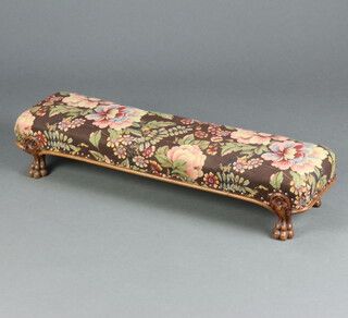 A Victorian carved walnut show frame footstool upholstered in floral material, raised on carved paw supports 16cm h x 84cm w x 22cm d 
