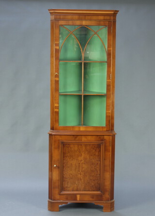A Georgian style yew double corner cabinet with moulded cornice, fitted shelves enclosed by astragal glazed doors, the base enclosed by a panelled door, raised on bracket feet 191cm h x 65cm w x 46cm d 