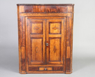 A Georgian oak hanging corner cabinet with moulded cornice and cupboard enclosed by a panelled door, the base fitted a drawer with tore handle, 119cm h x 94cm w x 56cm d 