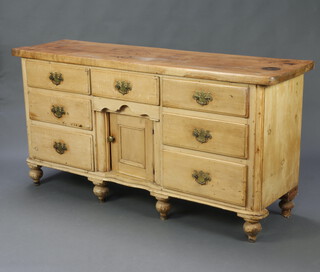 A 19th Century pine dresser base, fitted 7 drawers with replacement brass swan neck drop handles and cupboard enclosed by panelled doors, raised on bun feet 90cm h x 180cm w x 51cm d 