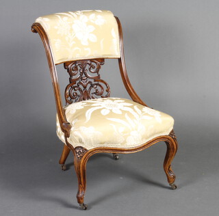 A Victorian walnut show frame nursing chair with pierced slat back, the seat and back upholstered in yellow and white floral material, raised on cabriole supports 78cm h x 52cm w x 44cm d (seat 39cm x 38cm) 
