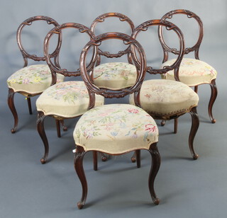 A set of 6 Victorian carved walnut balloon back dining chairs with over stuffed seats, raised on cabriole supports 