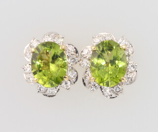 A pair of yellow metal oval peridot and diamond earrings, the peridot 4.8ct, the diamonds 0.65ct