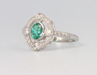 A platinum Art Deco style oval emerald and diamond ring, the centre stone approx 0.75ct, surrounded by brilliant cut diamonds approx. 0.4ct 3.8 grams, size N