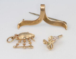 Two 9ct yellow gold charms 3.1 grams together with a 9ct yellow gold ribbon pin, gross weight 1.9 grams 