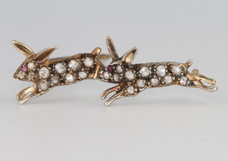 An Edwardian style yellow metal diamond and ruby brooch in the form of 2 running rabbits 35cmm, 2.1 grams 